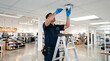 © solom - professional technician on a stepladder installing and adjusting a cctv security dome camera on the ceiling of a modern retail clothing store boutique