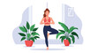 © Anar - Young woman practicing the yoga tree pose for balance and mindfulness in a bright room decorated with large green plants.