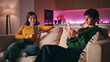 © stockbusters - Addicted friends scrolling mobile phones sitting separately home couch closeup.