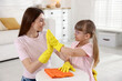 © New Africa - Spring cleaning. Happy mother and her daughter wiping dust from table together at home