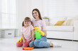 © New Africa - Spring cleaning. Happy mother and her daughter with detergent sitting on floor at home