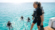 © Andres Mejia - Woman in scuba gear smiles near boat with divers in ocean