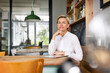 © Westend61 - Portrait of confident blond woman sitting at table