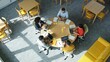 © Tama - People sit around a table working on laptops in a bright office space