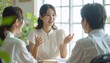 © Diamond Fuji - 半袖の夏ブラウス姿でチームメンバーに説明する日本人女性ビジネスウーマン・明るい緑あふれるオフィス