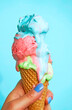 © VISTA by Westend61 - Woman's hand holding ice-cream cone with melting icecream in front of blue background
