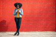 © VISTA by Westend61 - Young woman using smart phone while standing in front of red brick wall