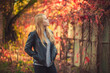 © Kathleen - Pensive blonde woman in black jacket outdoors with vibrant autumn foliage