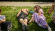 © Lustre Art Group  - Two children lying on grass and talking during summer play break. Concept of quiet conversation, emotional trust, social development, childhood connection and relaxed outdoor summer storytelling.