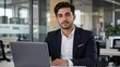 © Jhon - A young professional exudes confidence at a sleek desk in a modern office with natural side lighting.