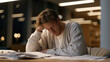 © forenna - Exhausted undergraduate slumped over grant application paperwork at university library table, research funding rejection letters scattered nearby, fluorescent overhead lighting casting harsh shadows