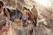 © Marko Geber - Friends hiking with trekking poles on a dry hillside trail
