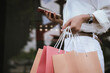 © Witoon - Close-up of a shopper carrying colorful shopping bags outdoors, symbolizing retail spending, consumer lifestyle, fashion purchases, and modern shopping experiences.
