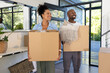 © Wavebreak Media - African American couple carrying cardboard boxes and holding fringed throw in bright entryway