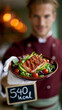 © Nick Freund - Kellner in roter Uniform präsentiert einen Teller mit einem Salat und einer Kreidetafel mit der Aufschrift 540 kcal.