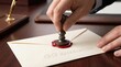 © Stitch - Hand pressing a metal stamp into red wax to seal a VIP reservation envelope