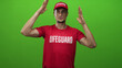 © Krakenimages.com - Lifeguard man in red shirt and cap frames his head with flat hands showing muscular forearms against green screen studio; vigilance duty.