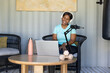 © Wavebreak Media - African woman sitting in nook wearing teal tee white headset recording podcast with laptop mic
