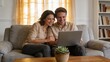 © ibhonk - Happy middle-aged couple smiles while using laptop together on sofa in living room