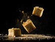 © sam - Cubes of baked dessert crumble in mid-air against a dark background