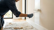 © solom - Professional painter wearing grey gloves using a paint roller to apply fresh white coat on an interior residential wall during a home renovation project