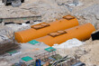 © Andrey - two large, bright orange cylindrical underground storage tanks resting in a dirt excavation pit during installation at an active construction site.