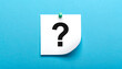 © qicoel - White paper note with question mark symbol pinned on a bright blue textured background, uncertainty concept