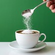 © MdMitzur - Sugar being poured from a spoon into a white cup of coffee