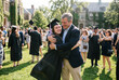 © Meow Creations - Proud father embracing daughter in cap and gown on graduation day