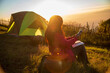 © aFotostock - Women camping outdoor sitting Tent Camp trip hiking mountain hill on sunrise. Picnic green nature campground Adventure Travel wildness forest. Tent camp in nature background flare sunlight mountain