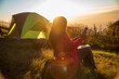 © aFotostock - Tent camp in nature background flare sunlight mountain. Women camping outdoor sitting Tent Camp trip hiking mountain hill on sunrise. Picnic green nature campground Adventure Travel wildness forest
