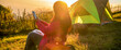 © aFotostock - Banner Women camping outdoor sitting Tent Camp trip hiking mountain hill on sunrise. Picnic green Adventure Travel forest with copy space. Panorama Tent camp nature background flare sunlight mountain