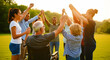 © MARGARYAN GOR - Diverse group of people holding hands in a circle with a man in a wheelchair. Multi-generational community raising arms together at sunset. Unity and inclusion concept for social welfare marketing.