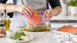 © tom - Chef Marinating Raw Salmon Fillet in Vacuum Bag with Herbs and Olive Oil