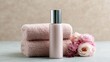 © Firadoaw - Elegant cosmetic bottle surrounded by soft towels and pastel floral arrangement, clean skincare editorial aesthetic