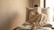 © MHK01 - Woman reading a book while wrapped in a cozy knitted blanket on a comfortable sofa in a bright room