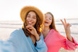 © maxbelchenko - Two happy girlfriends are having fun on the seashore at sunset. Beautiful women are relaxing and spending time on the beach. A concept of beauty, fun, and friendship. An active lifestyle.
