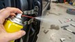 © Wan - Hand sprays lubricant on car door hinge for maintenance
