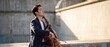 © Dinali - Asian cellist playing cello outdoors at concrete structure in warm golden light, elegant male musician performing classical music on instrument, serene and focused creative artist expression.