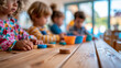 © Nataliya - Close-up of young children playing together at a wooden table in a bright modern learning environment, early learning concept, child table photography, kindergarten lifestyle