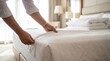 © Stitch - Housekeeper pulling white bed sheet while making bed in hotel room