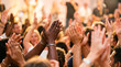 © Fadilah - Multiethnic audience clapping hands and cheering at a celebratory event live performance or religious worship gathering with warm golden lighting