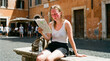© catocala - Scandinavian woman studies map while sitting on stone bench in Rome during a sunny day