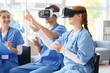 © Pixel-Shot - Medical students using virtual reality headsets and controllers during healthcare training simulation in classroom, nursing education with immersive technology and teamwork