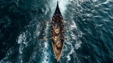 Aerial view of a longboat with many rowers navigating the choppy ocean waters.