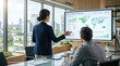 © iona - Professional woman presenting global renewable energy portfolio on large screen to colleague in modern conference room, pointing at world map and bar charts