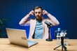© Serhii - Man podcaster influencer blogger smiling while broadcasting his live audio podcast in studio using headphones. Male radio host making podcast or interview