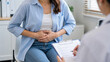 © Chau Tan - Female patient with abdominal pain consulting doctor in clinic for digestive health diagnosis