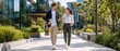© Vasiliy - Happy business colleagues walking outdoors with laptop and coffee. Young professional man and woman in smart casual attire talking in modern office park. Casual corporate lifestyle