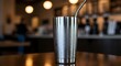 © Momo - Stainless steel tumbler with straw on wooden table in cafe